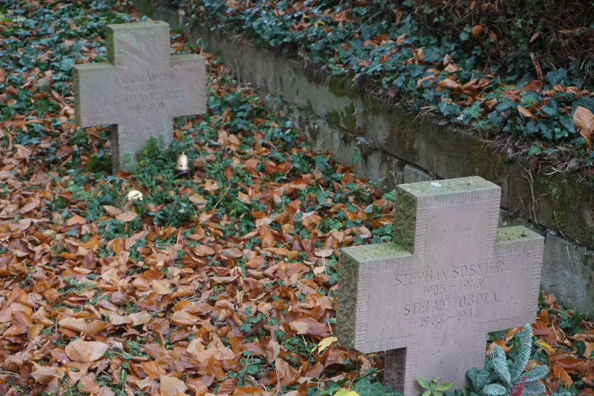 Dwa kamienne krzyże z podwójnymi napisami przy murku, wśród liści i bluszczu; przy lewym znicze.
Napis: „ANTONI WN?? 1910–1940 | MICHAEL WR?ESZC? 1908–193? | STEPHAN SOSNIERZ 1905–1945 | STEFAN TOBOLA 1905–1940”