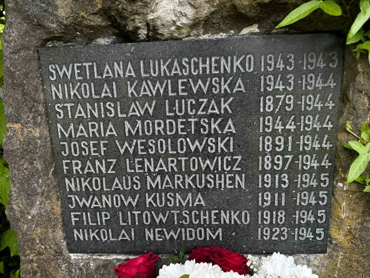 Unterkochen: tablica z nazwiskami — zbliżenie.
Napis: „SWETLANA LUKASCHENKO 1943–1943 · NIKOLAI KAWLEWSKA 1943–1944 · STANISLAW LUCZAK 1879–1944 · MARIA MORDETSKA 1944–1944 · JOSEF WESOLOWSKI 1891–1944 · FRANZ LENARTOWICZ 1897–1944 · NIKOLAUS MARKUSHEN 1913–1945 · JWANOW KUSMA 1911–1945 · FILIP LITOWTSCHENKO 1918–1945 · NIKOLAI NEWIDOM 1923–1945”